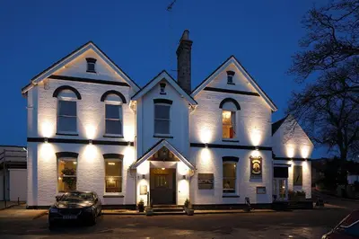 a white house with a car parked in front of it at Thomas Paine Hotel in Thetford