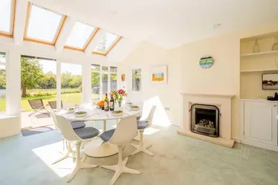 a dining room with a table and chairs and a fireplace at Claysmead - A large Lakeside House in Thorpeness - Aldeburgh Coastal Cottages in Thorpeness