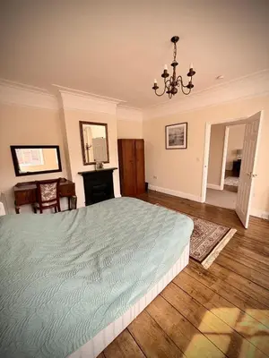 a bedroom with a large bed and a chandelier at Churchgate Apartment in Bury Saint Edmunds