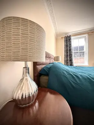 a lamp on a wooden table next to a bed at Churchgate Apartment in Bury Saint Edmunds