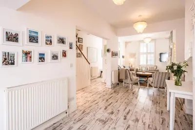 a living room with white walls and a table and chairs at La Ronessa, Aldeburgh in Aldeburgh