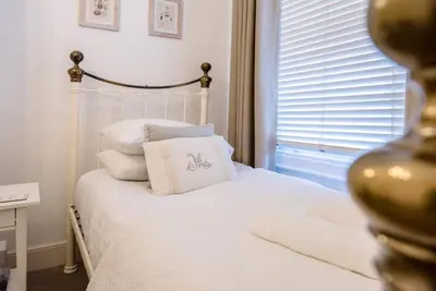 a white bed with a pillow and a window at La Ronessa, Aldeburgh in Aldeburgh
