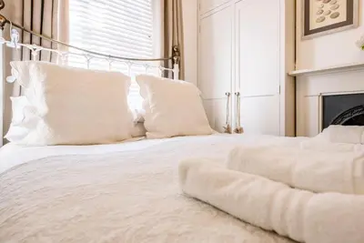 a bedroom with a white bed with white pillows at La Ronessa, Aldeburgh in Aldeburgh