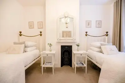 a white room with two beds and a fireplace at La Ronessa, Aldeburgh in Aldeburgh