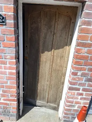 a large wooden door in a brick building at Harleston Norfolk Suffolk border Historic Cottage in Harleston