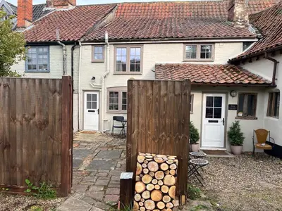 a fence with logs in front of a house at Harleston Norfolk Suffolk border Historic Cottage in Harleston