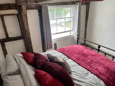 a bedroom with a bed with red pillows and a window at Harleston Norfolk Suffolk border Historic Cottage in Harleston