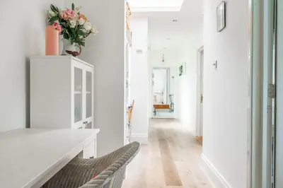 a white hallway with a table and a chair at Danes House 4 in Aldeburgh