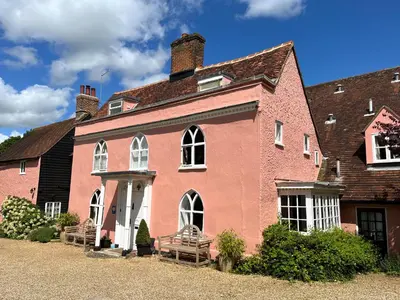 a large pink building with white windows and a roof at Little rooms at The Cottage in Bishops Stortford
