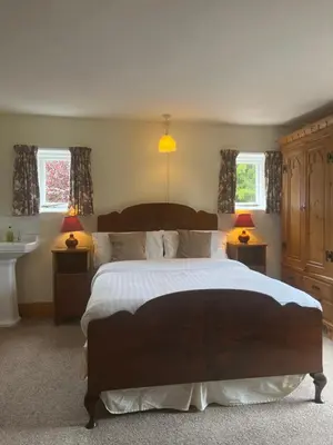 a bedroom with a large bed and two windows at Little rooms at The Cottage in Bishops Stortford