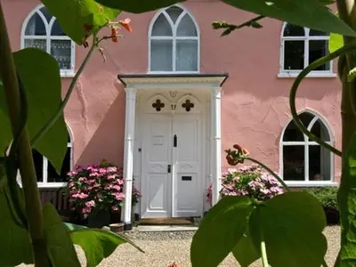 a pink house with a white door and some flowers at Little rooms at The Cottage in Bishops Stortford