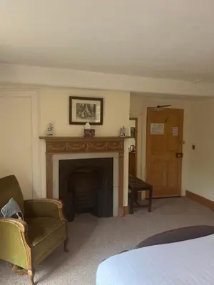 a room with a fireplace with a chair and a bed at Little rooms at The Cottage in Bishops Stortford