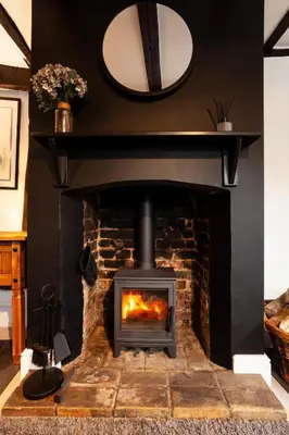 a fireplace in a living room with a mirror on the wall at 2 Bedroom Cottage in Debenham - The Old Toll House in Debenham