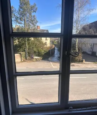 a window with a view of a street seen through it at 2 Bedroom Cottage in Debenham - The Old Toll House in Debenham