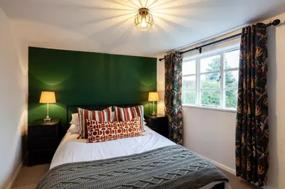 a bedroom with a bed and a green wall at 2 Bedroom Cottage in Debenham - The Old Toll House in Debenham