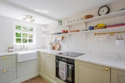 a kitchen with white cabinets and a sink and a stove at Boutique Suffolk Cottage Cosy Family Holiday Home with Garden Near Aldeburgh in Kettleburgh