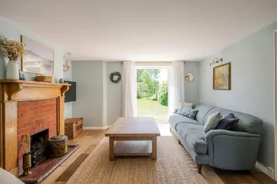 a living room with a couch and a fireplace at Boutique Suffolk Cottage Cosy Family Holiday Home with Garden Near Aldeburgh in Kettleburgh