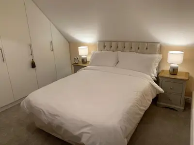 a bedroom with a large white bed with two lamps at The Pightle Annexe in Saffron Walden