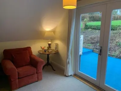 a room with a chair and a table and a sliding glass door at The Pightle Annexe in Saffron Walden