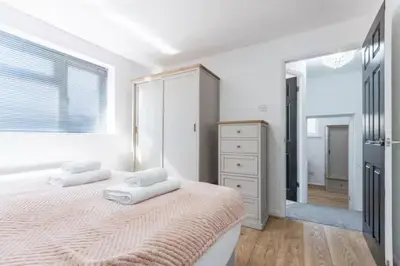 a white bedroom with a large bed and a mirror at Stylish and comfortable 4-Bedroom Retreat in the Heart of Chelmsford in Chelmsford