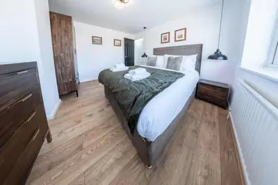 a bedroom with a large bed and a wooden floor at Stylish and comfortable 4-Bedroom Retreat in the Heart of Chelmsford in Chelmsford