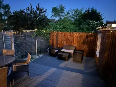 a patio with a table and chairs and a fence at Stylish and comfortable 4-Bedroom Retreat in the Heart of Chelmsford in Chelmsford
