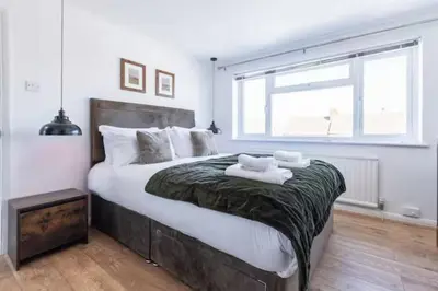 a bedroom with a large bed with two towels on it at Stylish and comfortable 4-Bedroom Retreat in the Heart of Chelmsford in Chelmsford