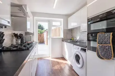 a kitchen with a stove and a washing machine at Stylish and comfortable 4-Bedroom Retreat in the Heart of Chelmsford in Chelmsford