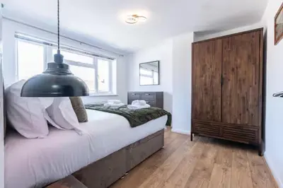 a bedroom with a large bed and a black lamp at Stylish and comfortable 4-Bedroom Retreat in the Heart of Chelmsford in Chelmsford