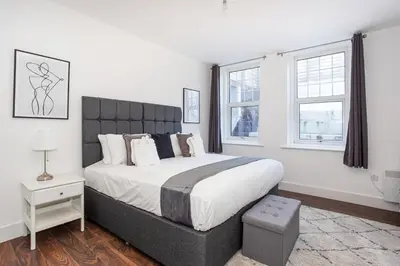 a bedroom with a large bed and two windows at Stylish & Modern Home by the Sea Near Three Shells in Southend-on-Sea