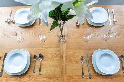 a table with plates and silverware and a vase with flowers at Stylish & Modern Home by the Sea Near Three Shells in Southend-on-Sea