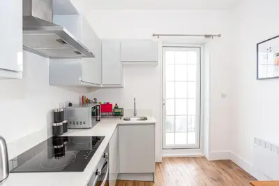 a white kitchen with white appliances and a window at 3 Bed Apartment with Balcony in Southend on Sea! in Southend-on-Sea