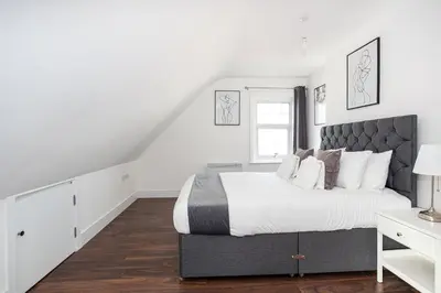 a white bedroom with a large bed and a window at 3 Bed Apartment with Balcony in Southend on Sea! in Southend-on-Sea