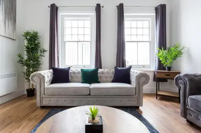 a living room with a couch and two windows at 3 Bed Apartment with Balcony in Southend on Sea! in Southend-on-Sea