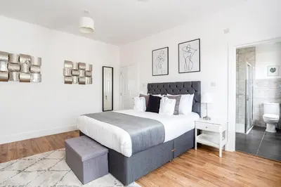 a white bedroom with a large bed and a bathroom at 3 Bed Apartment with Balcony in Southend on Sea! in Southend-on-Sea