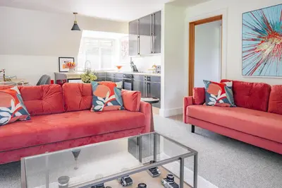 a living room with two red couches and a kitchen at The Flat - Waresley Park Estate