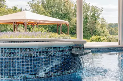a swimming pool with a fountain and an umbrella at The Flat - Waresley Park Estate
