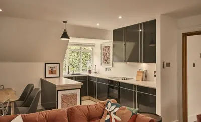 a living room with a couch and a kitchen at The Flat - Waresley Park Estate