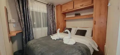 two swans sitting on a bed in a bedroom at Dancing Seagulls Caravan in Clacton-on-Sea