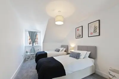 a bedroom with two beds and a window at Modern town centre apartment in Bishops Stortford