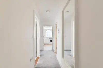 an empty hallway with white walls and a mirror at Modern town centre apartment in Bishops Stortford