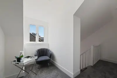 a white room with a chair and a desk at Modern town centre apartment in Bishops Stortford