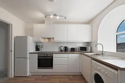 a kitchen with white cabinets and a white refrigerator at Modern town centre apartment in Bishops Stortford