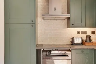a kitchen with green cabinets and a stove top oven at Beech Cottage - one bedroom retreat with hot tub in Hatfield Broad Oak