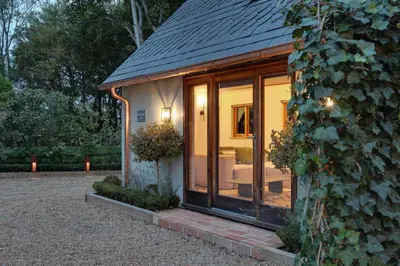 a small house with a large glass door at Beech Cottage - one bedroom retreat with hot tub in Hatfield Broad Oak