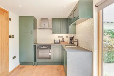 a kitchen with green cabinets and a counter at Beech Cottage - one bedroom retreat with hot tub in Hatfield Broad Oak