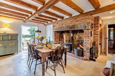 a dining room with a table and a brick fireplace at 4 Bed in Sudbourne oc-w32267 in Sudbourne