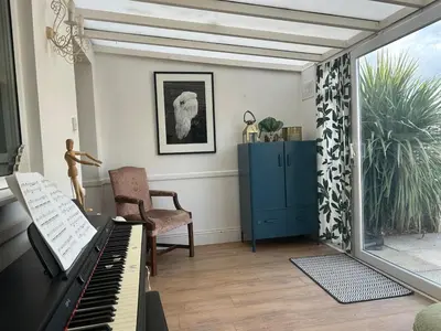 a living room with a piano and a blue cabinet at Cosy island home near beach in West Mersea
