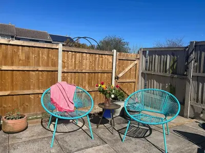 two chairs and a table on a patio with a fence at Cosy island home near beach in West Mersea
