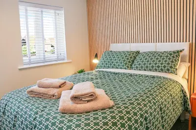 a bedroom with a green bed with towels on it at Stylish 2 Bedroom Property in Bury Saint Edmunds